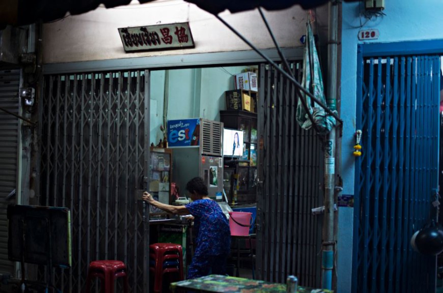 Una mujer entra en su casa del distrito de Samphanthawong donde una televisión emite una telenovela/ Foto: Walter Astrada