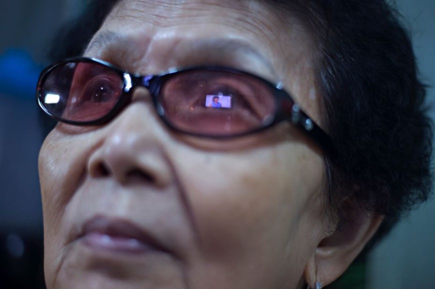 Una pantalla de televisión es reflejada en las gafas de una mujer que mira una telenovela en el interior de su casa en el barrio de Chinatown de Bangkok / Foto: Walter Astrada 