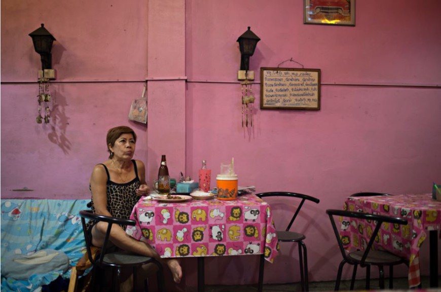 Una mujer mira una telenovela mientras cena en el interior de un restaurante en el distrito de Samphanthawong de Bangkok / Foto: Walter Astrada