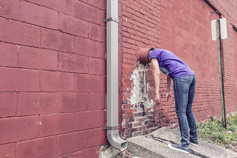 Una mujer con un cubo en la cabeza se da contra un muro