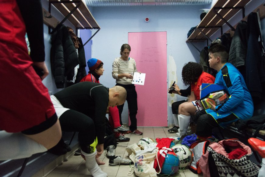 Antes de un partido, las jugadoras se congregan en los vestuarios. Karine, entrenadora suplente, da las últimas instrucciones antes de salir al terreno de juego. 