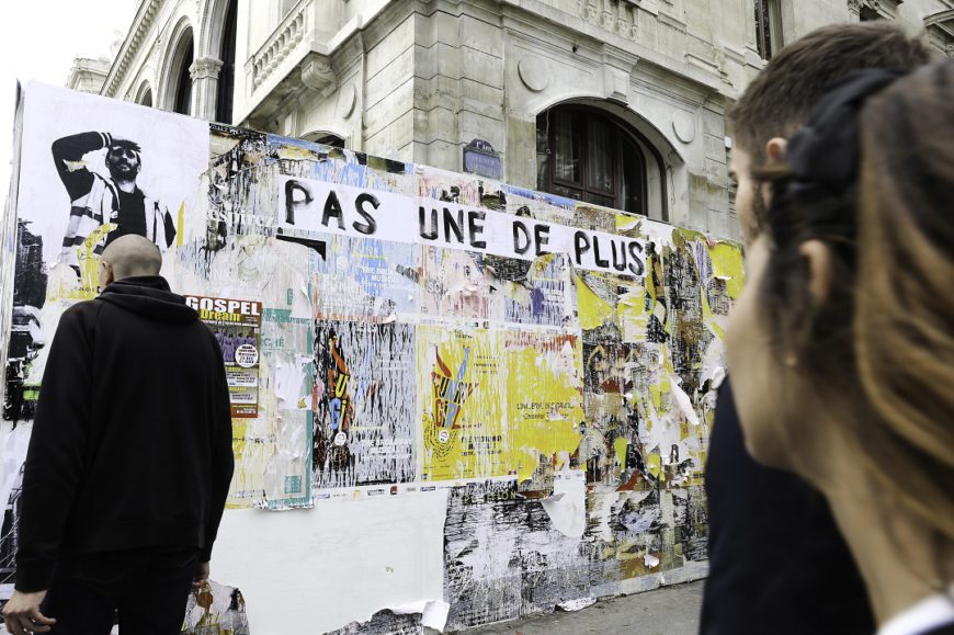 Una pared llena de carteles y la gente está pasando por delante. Francia