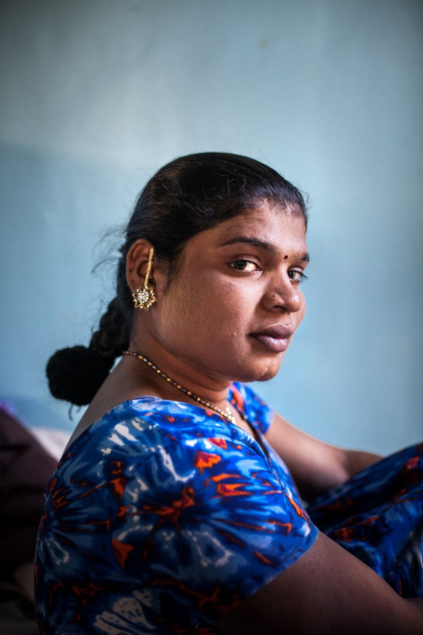 Retrato de una mujer india con vestido azul y una trenza en el pelo. Lleva joyas doradas y el tradicional bindi en la frente. 