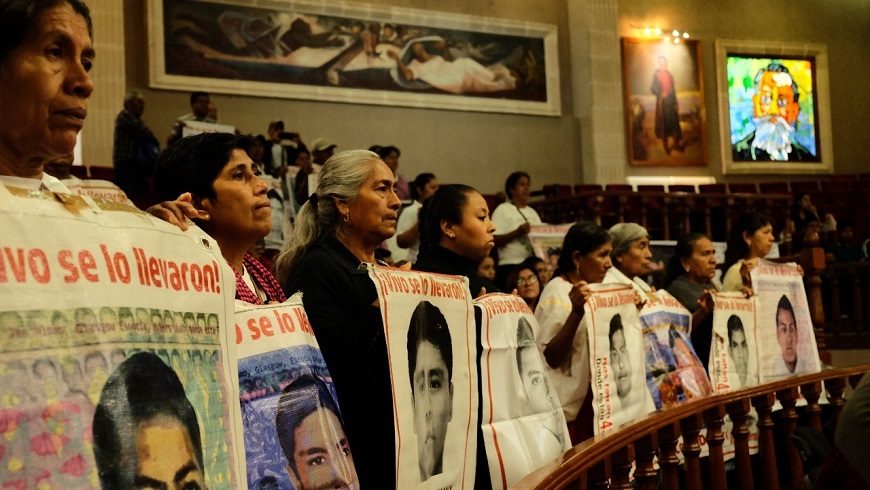 varias mujeres en fila sostienen carteles con fotos de mujeres