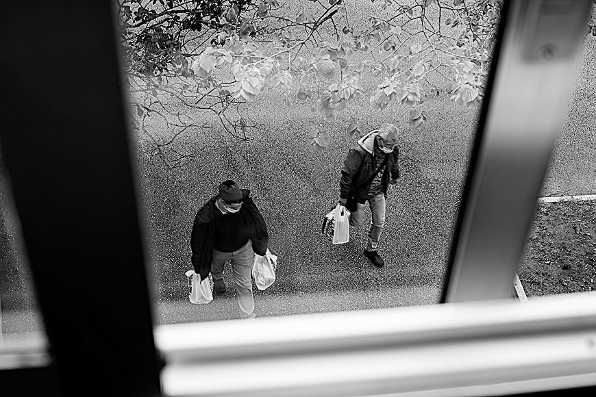 se ve desde la ventana a dos personas con bolsas de la compra