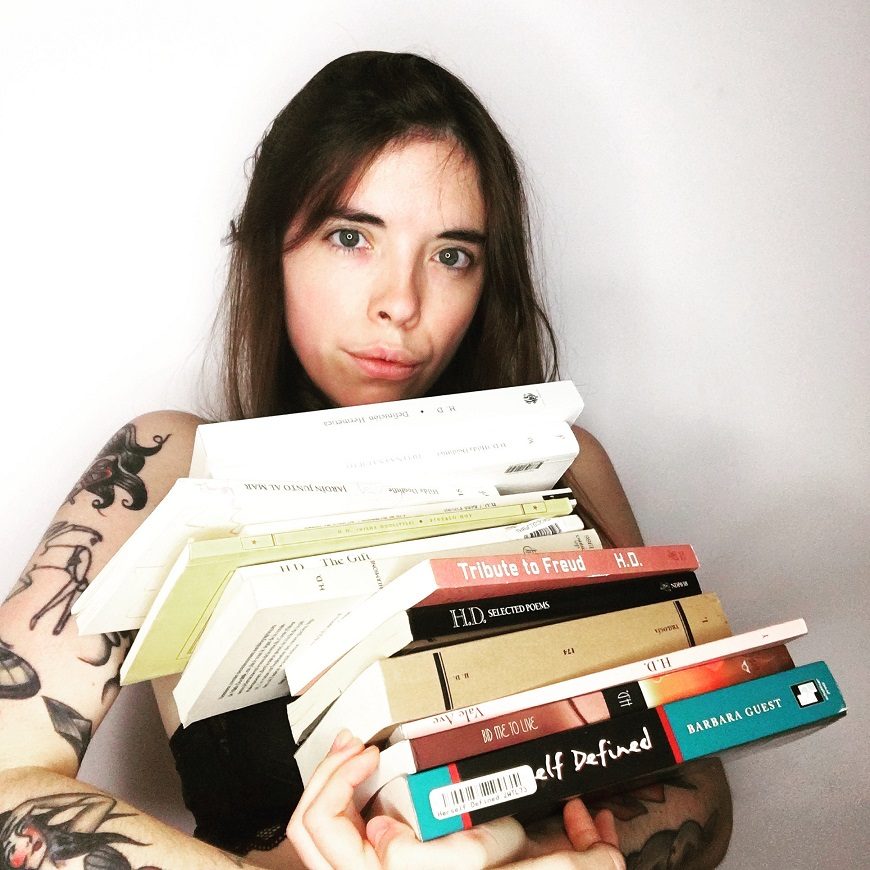 una mujer de medio cuerpo sosteniendo una pila de libros