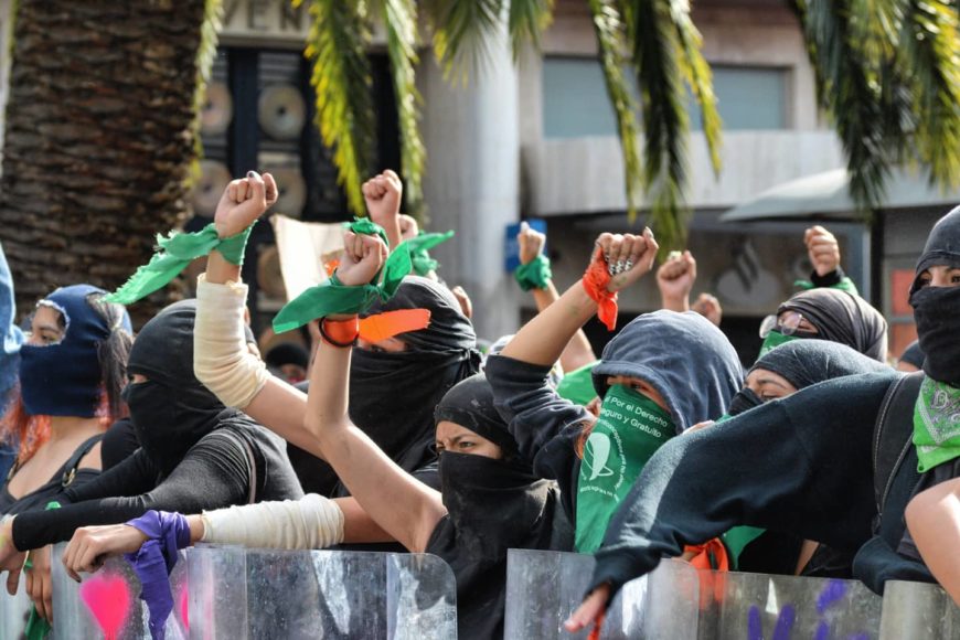 mujeres con la cara tapada y el pañuelo verde por el aborto se manifiestan parapetadas