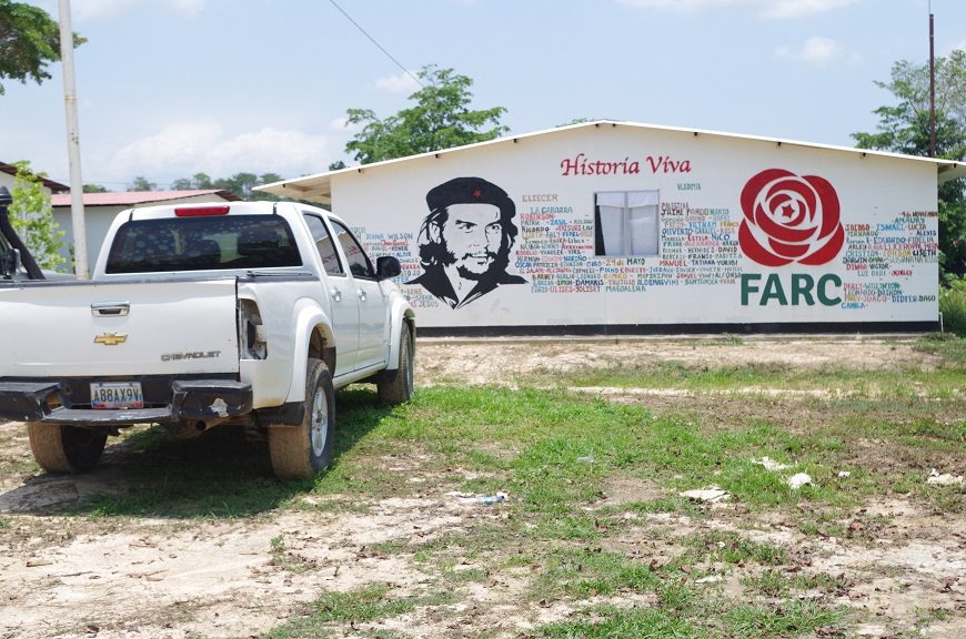 una pickup frente a una pared blanca donde se lee FARC hay una imagen del Che Guevara y muchas palabras escritas