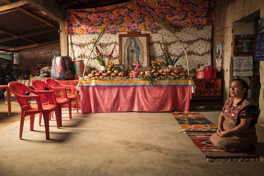 una mujer al lado de su altar por el Día de Muertos