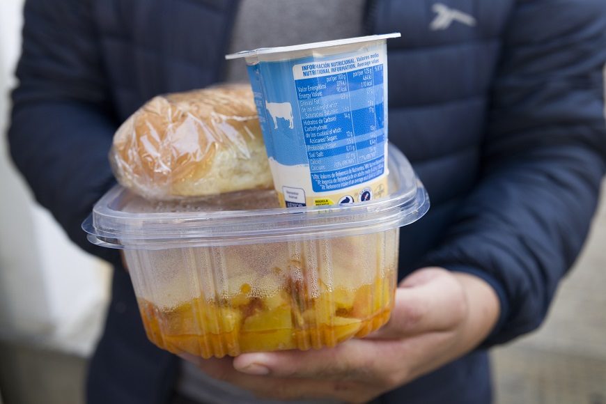 primer plano de un tupper, un yogur y un bollo de pan