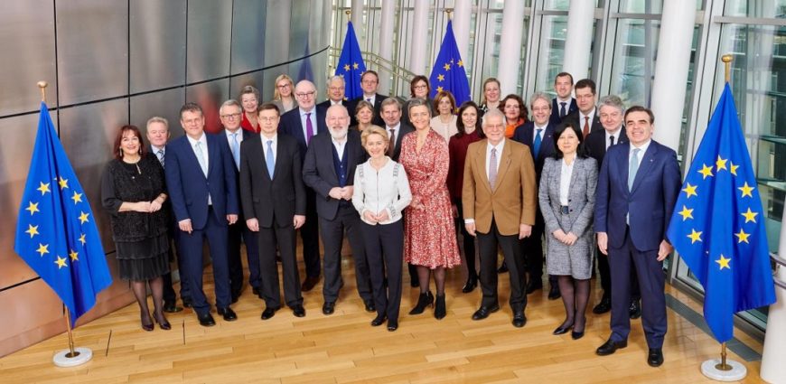 un grupo de hombres y mujeres posa junto a banderas de la Unión Europea