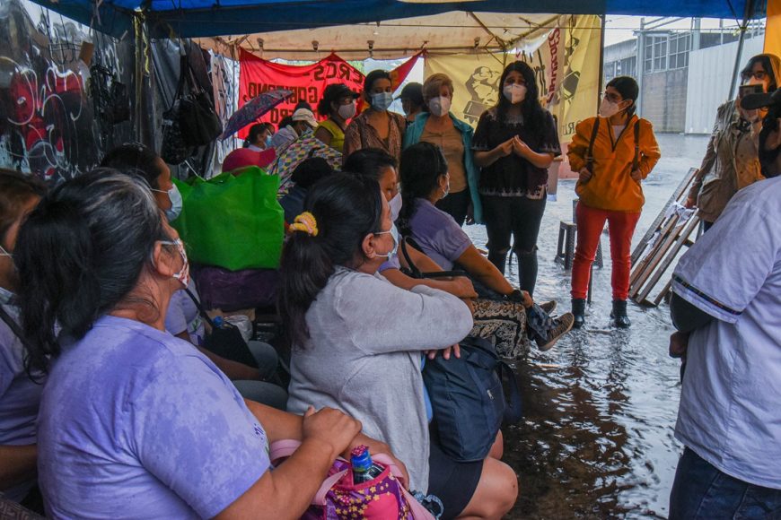 Un grupo de mujeres habla en la calle, bajo una lona