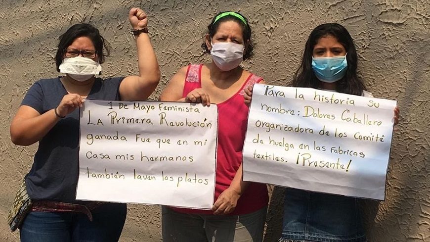 Tres mujeres con mascarillas portan carteles reivindicativos