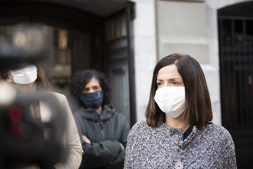 una mujer, con mascarilla, grabada con una cámara