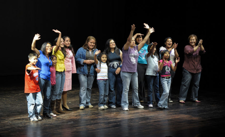 un grupo de mujeres y niñas saluda desde lo alto de un escenario