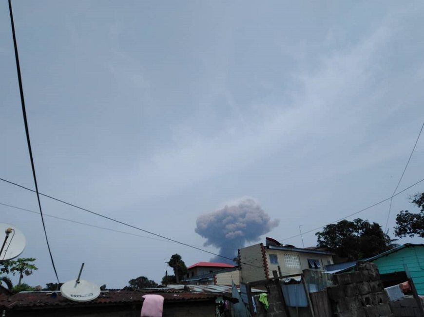 se ve el cielo y una nube de una explosión, sobre los tejados de casas