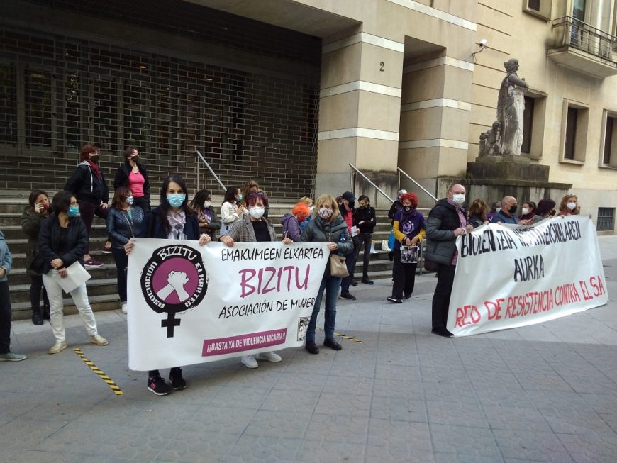 un grupo de personas sostienen dos pancartas frente a los juzgados