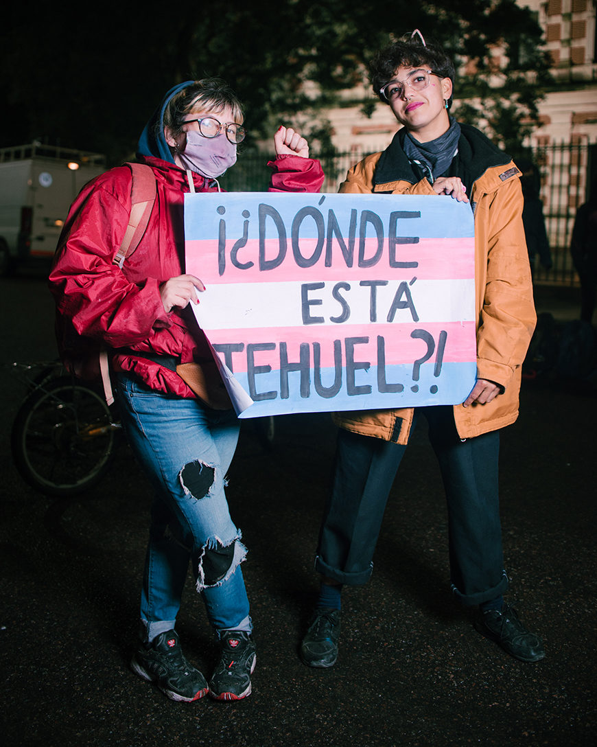 Dos personas jóvenes agarran una pancarta, con los colores de la bandera de las personas trans, en la que aparece escrita "¿Dónde está Tehuel?"