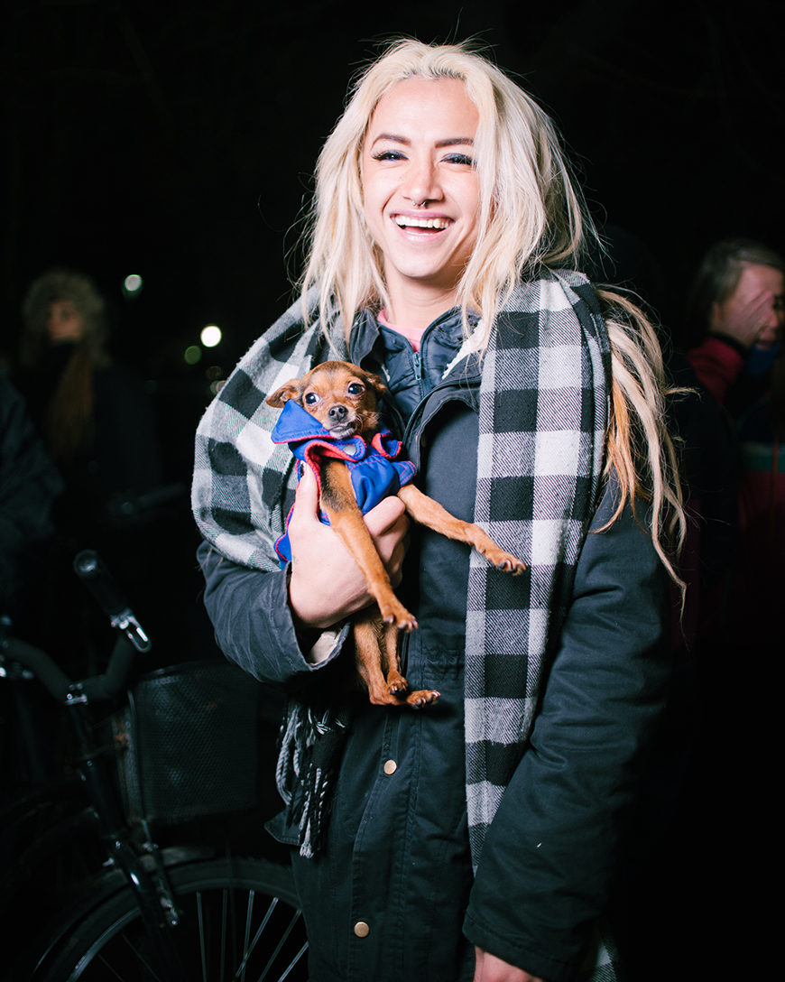 Una mujer rubia con un perro en la mano posa sonriente durante una marcha a favor de los derechos de las personas trans en Argentina.