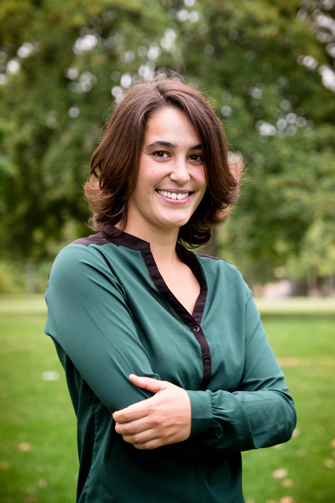 una mujer posando en un parque, de medio cuerpo y sonriendo